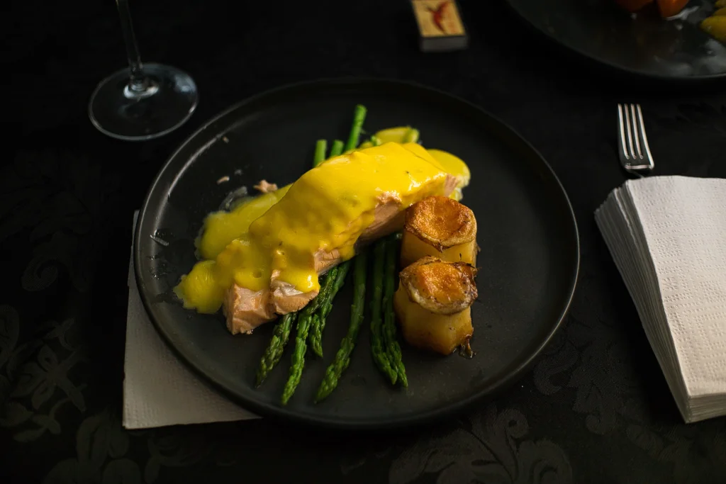A close view of salmon with asparagus on a dark plate